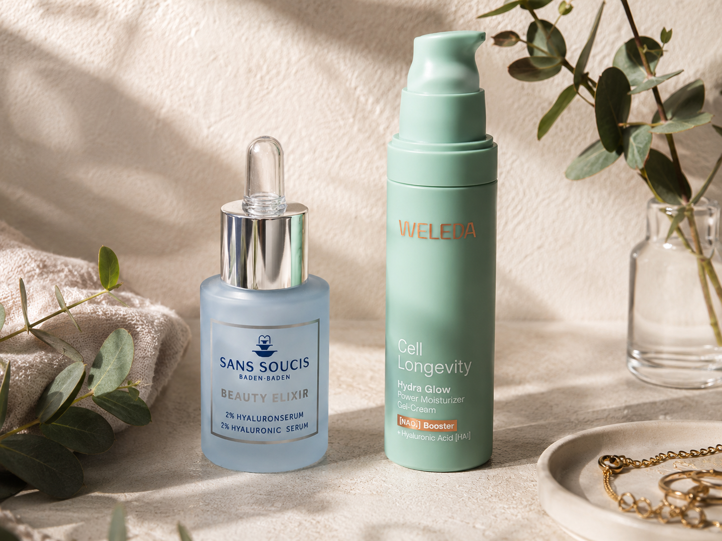 Sans Soucis Hyaluronserum und Weleda Cell Longevity Gel-Creme zwischen   Eukalyptuszweigen – nachhaltige Skincare