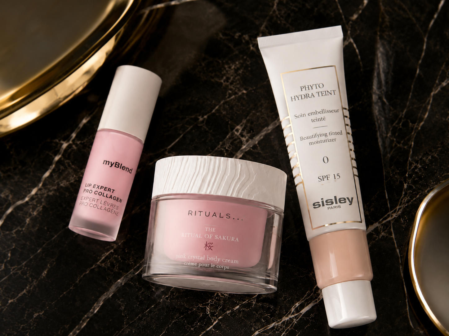 Luxus-Gesichtspflege auf dunklem Marmor: myBlend Lip Expert Pro Collagen, Rituals The Ritual of   Sakura Body Cream und Sisley Phyto Hydra Teint SPF 15