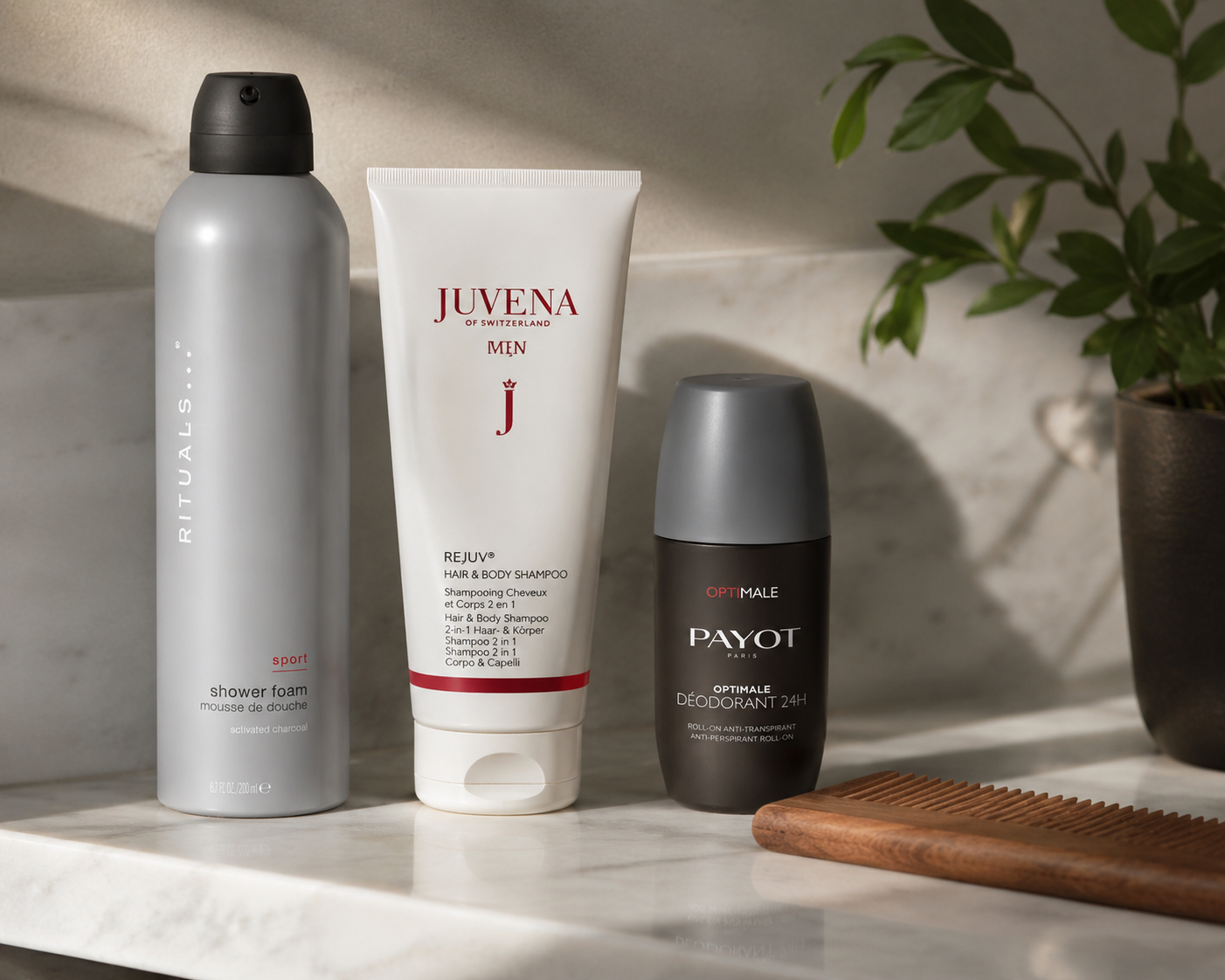 Körperpflege für Männer auf Marmor: Rituals Sport Shower Foam, Juvena Men Rejuv Hair & Body   Shampoo und Payot Optimale Deodorant 24H neben einem Holzkamm