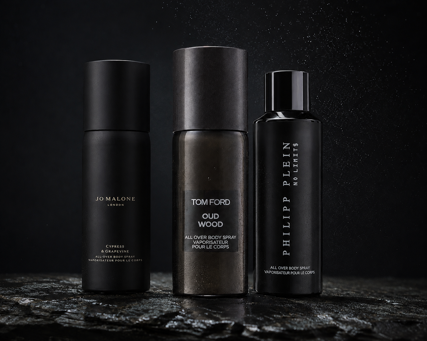 Drei schwarze Bodysprays von Jo Malone, Tom Ford und Philipp Plein auf einer feuchten dunklen Steinfläche mit feinen Sprühtröpfchen im Hintergrund.
