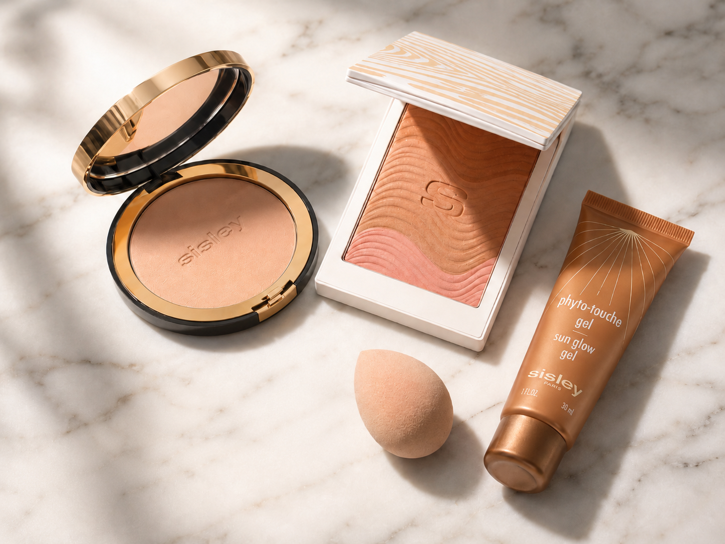 Sisley Kompaktpuder, Phyto-Touches Bronzing-Puder, Make-up-Schwamm und Phyto-Touche Sun Glow Gel   auf Marmor