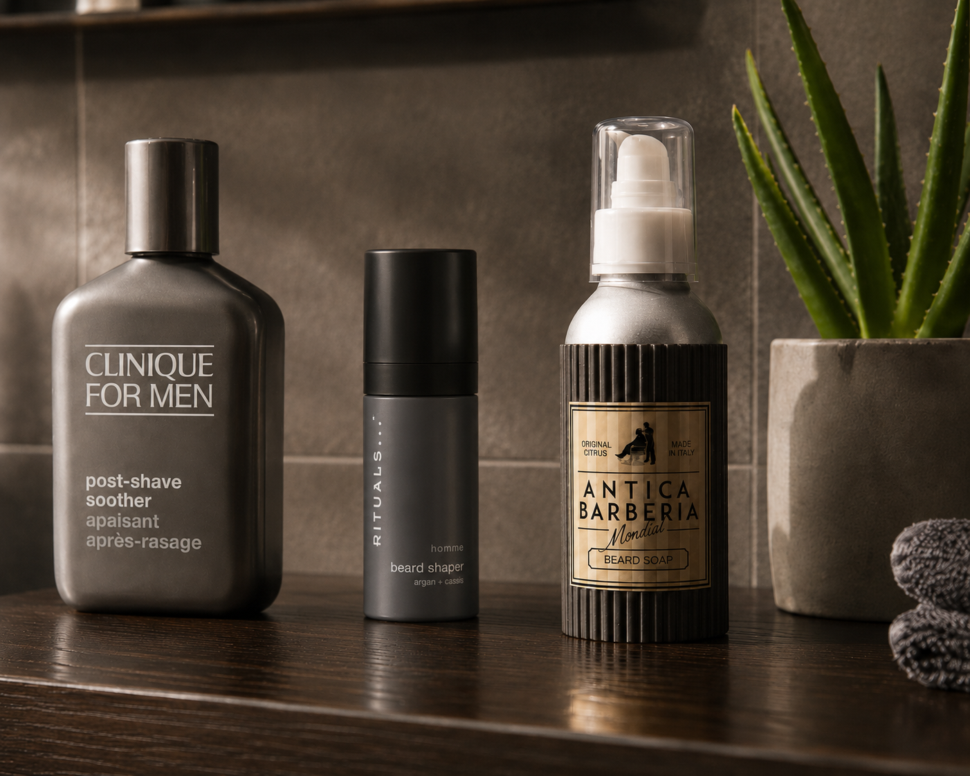 Herren-Rasurpflege im Badezimmer: Clinique For Men Post-Shave Soother, Rituals Homme Beard Shaper   und Antica Barberia Mondial Beard Soap neben einer Aloe-Vera-Pflanze
