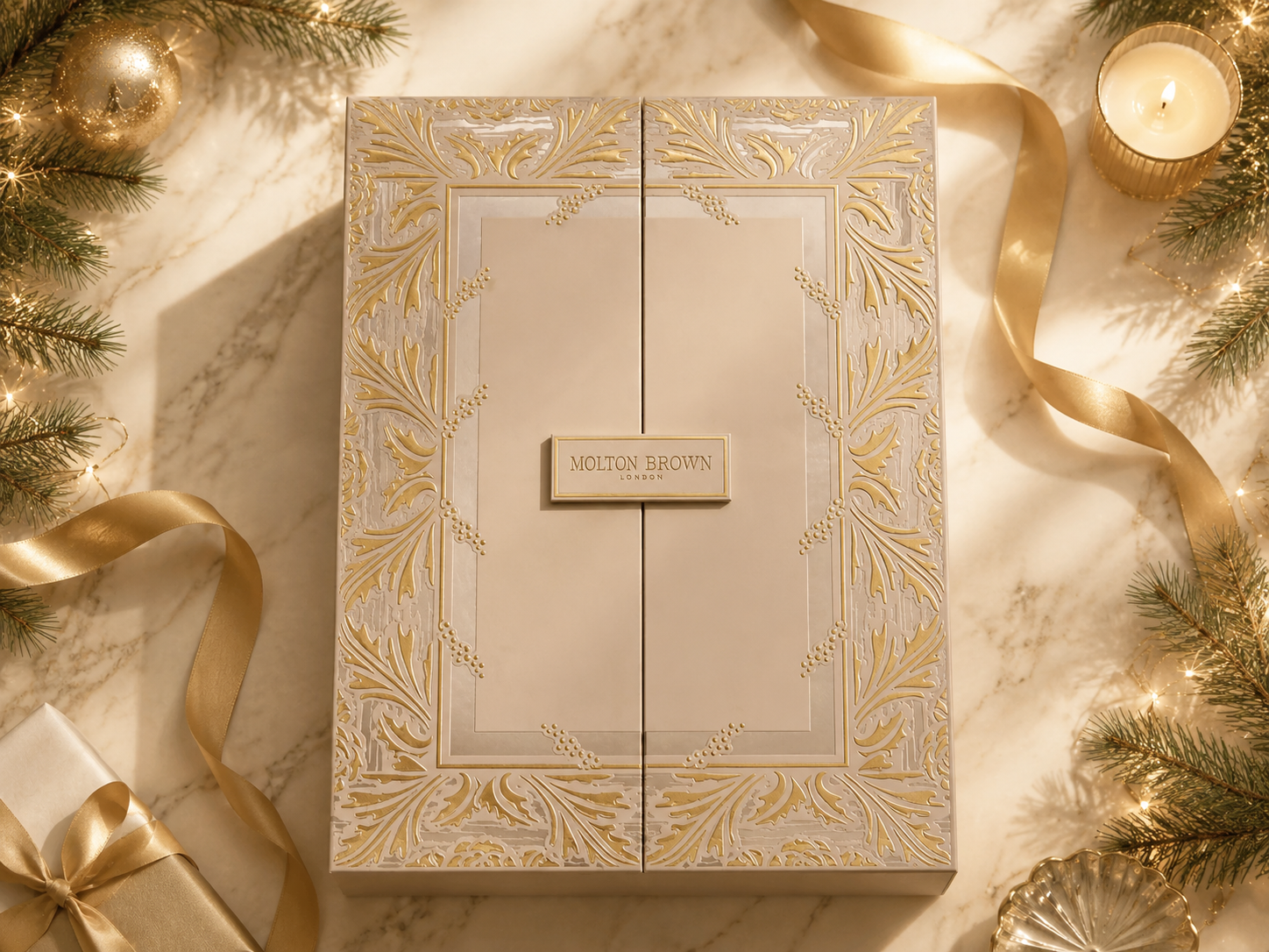Molton Brown Adventskalender mit goldenem Ornament-Design auf hellem Marmor, umrahmt von   Tannenzweigen, Kerze und goldenem Geschenkband
