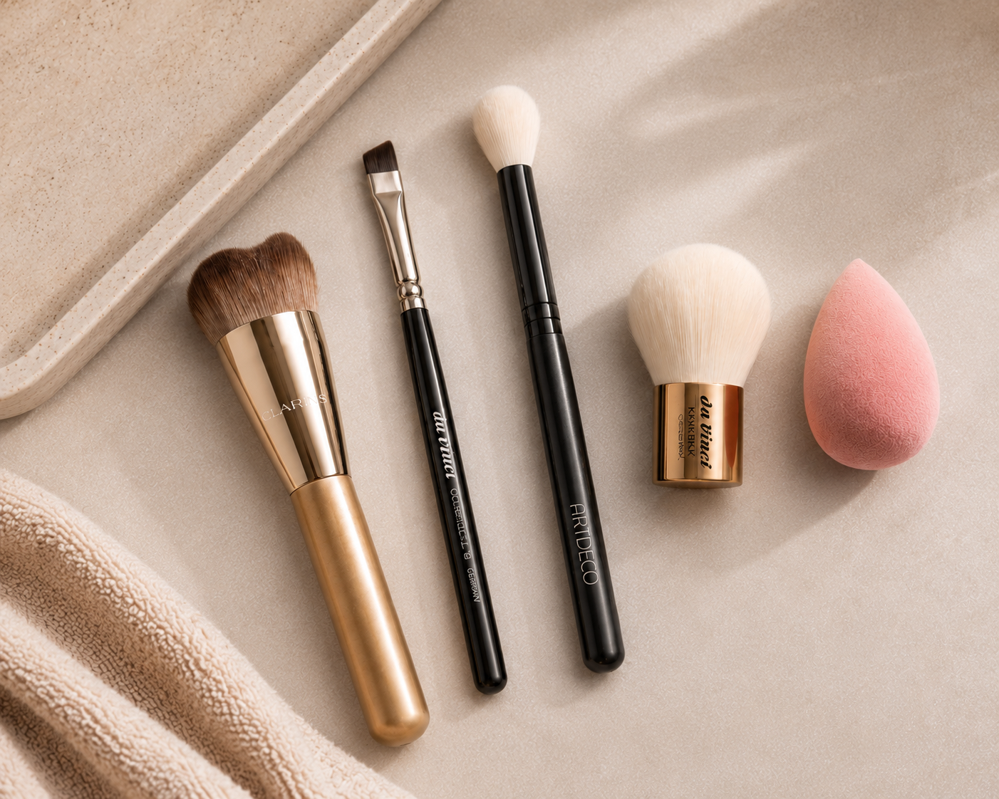 Flatlay von Pinseln in verschiedener Größe und einem Beauty Blender auf einer Marmorplatte